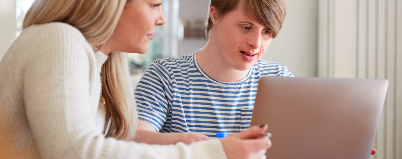 Female CDCP assists a teen male client sitting with a laptop